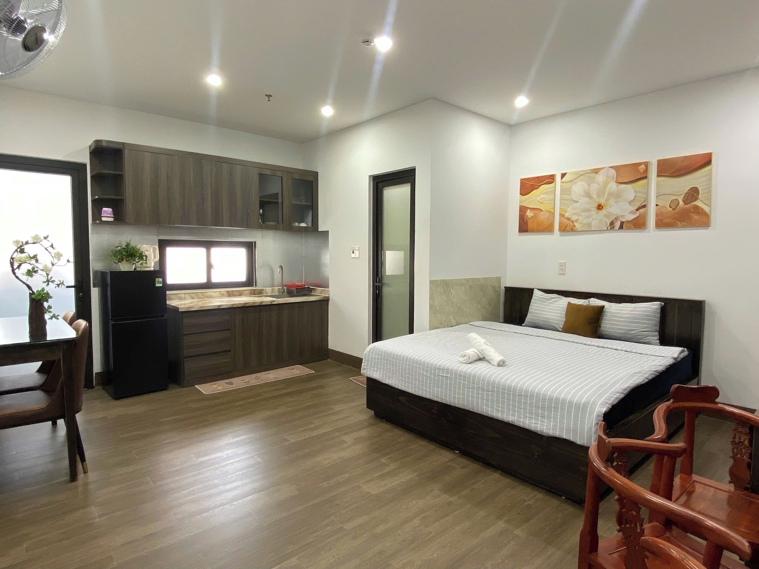 A compact hotel room with a bed, a small kitchenette, a dining area, and a bathroom.