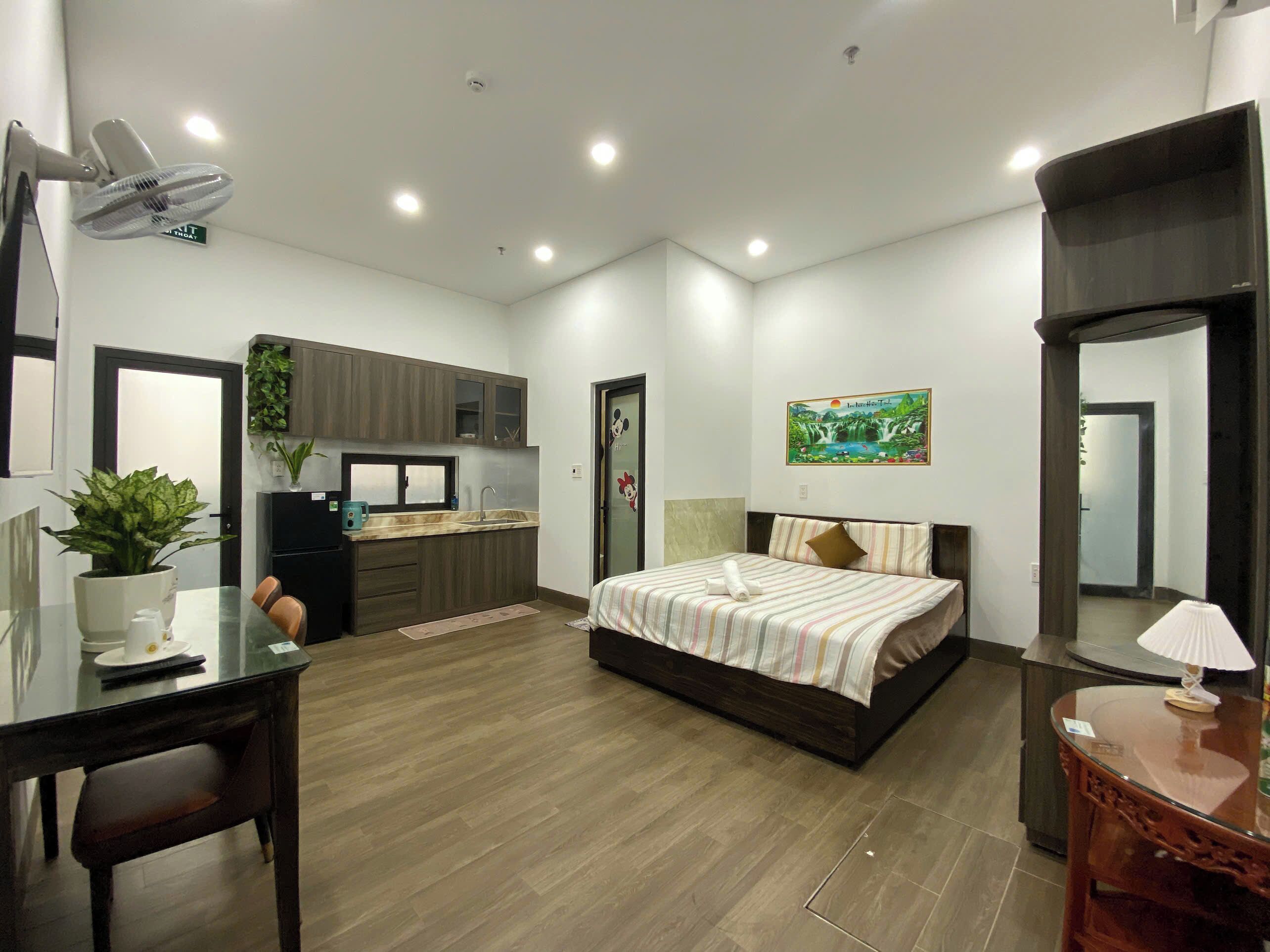 A modern bedroom with a bed, bedside table, lamp, and a small desk with a chair.