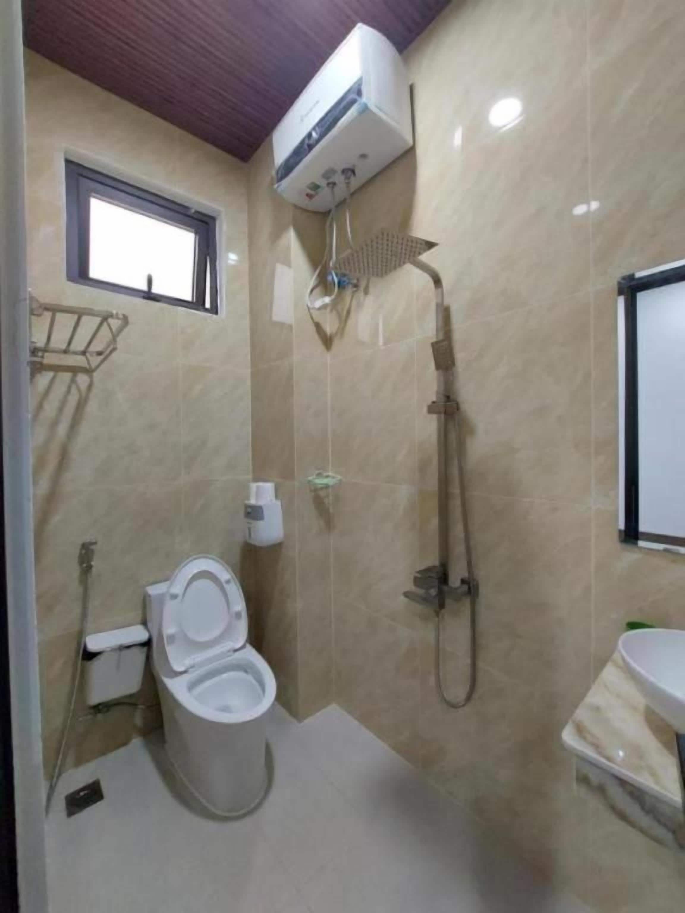 Casa de banho com sanita, chuveiro e lavatório.