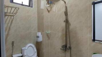 Casa de banho com sanita, chuveiro e lavatório.