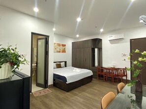 A modern hotel room with a bed, a desk, a chair, a dining table, and a potted plant. - An Thinh Boutique Apartment Da Nang (Da Nang)