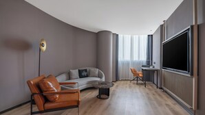 A modern living room with a curved ceiling, a leather sofa, a coffee table, a TV, and a small table with a chair.