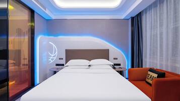 Una habitación de hotel moderna con una cama grande, un escritorio con una silla, un sofá y una pared con un diseño de iluminación original.