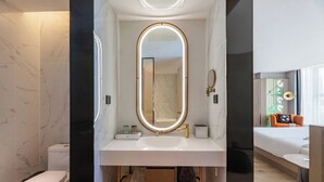 A modern bathroom with a white vanity, a large mirror, and a toilet.