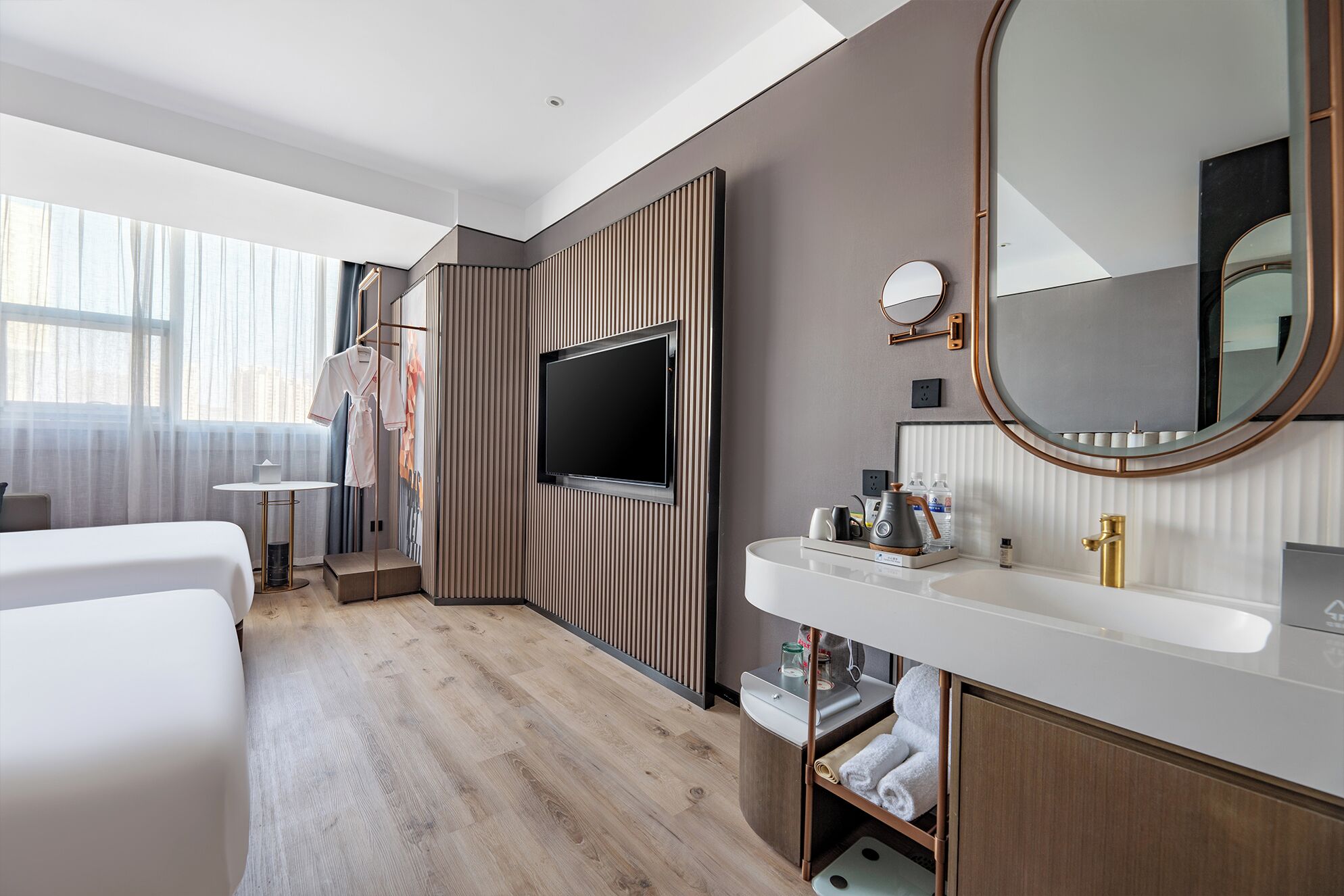 Una habitación de hotel moderna con una televisión, un espejo grande, una tocador con lavabo y una cama.