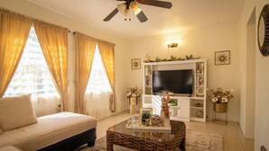 Ein Wohnzimmer mit einer Couch, einem Couchtisch, einem Fernseher und einem Deckenventilator.