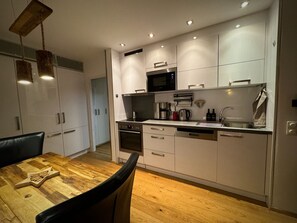 Eine moderne Küche mit weißen Schränken, einem Holzespeisetisch und einem schwarzen Stuhl.