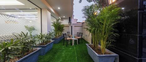 A modern outdoor patio with artificial grass, potted plants, and a dining area.