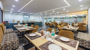 A modern dining area with tables set for two, equipped with cutlery and condiments, and a patterned bench seating area.