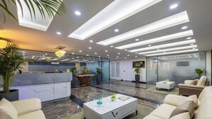A modern lobby with a reception desk, seating area, and a large plant.