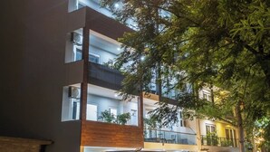 A multi-story hotel with illuminated signage, outdoor parking, and surrounding greenery.