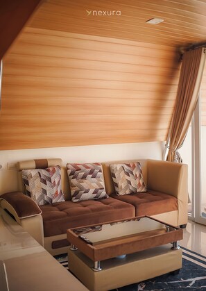 Una sala moderna con sofá, cojines estampados, una mesa de centro y techo de madera.