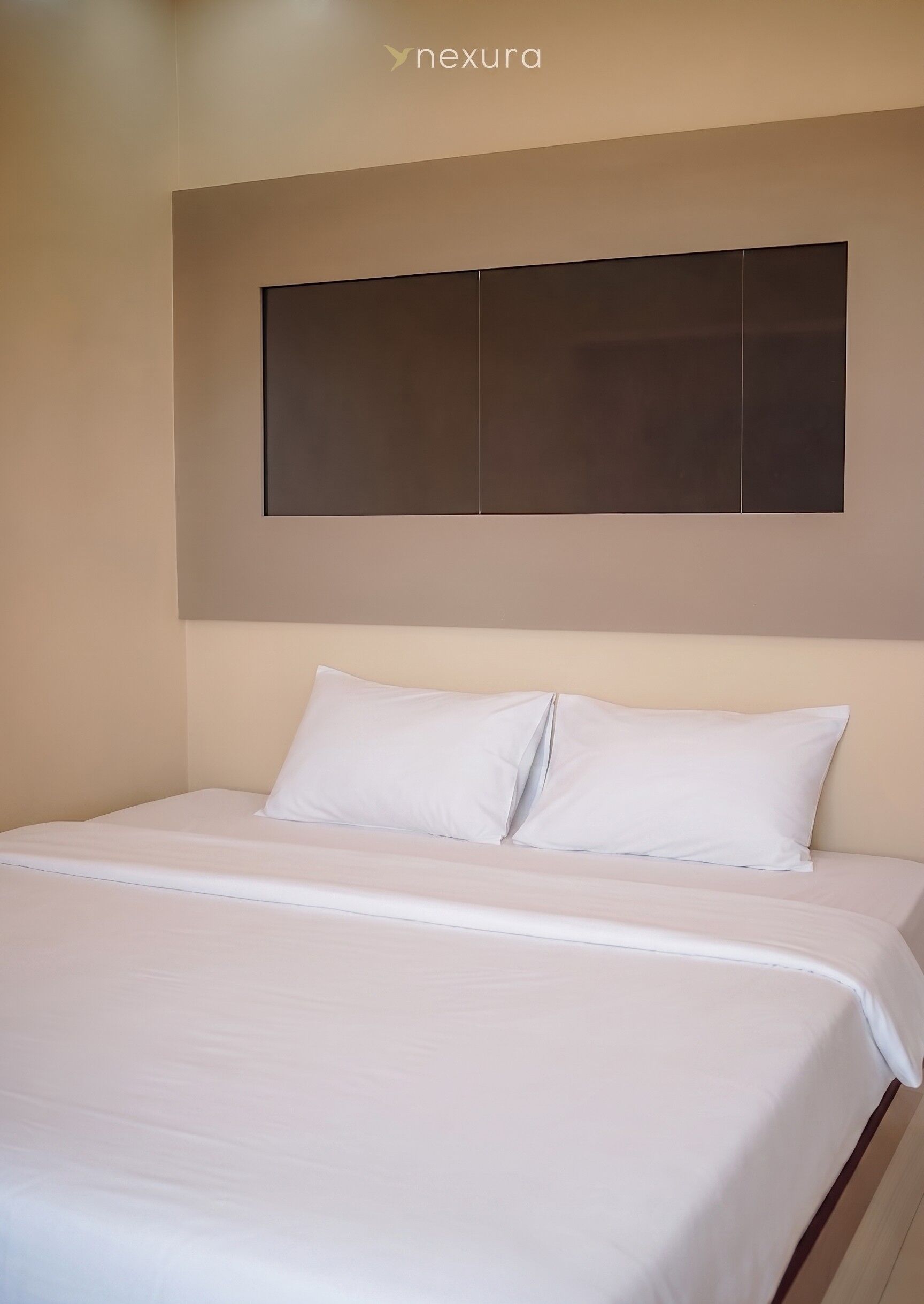 A hotel room with a bed, white bedding, a headboard, and a wall-mounted panel.