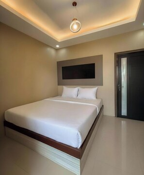 Un dormitorio moderno con una cama grande, un televisor de pantalla plana en la pared y una puerta a la derecha.