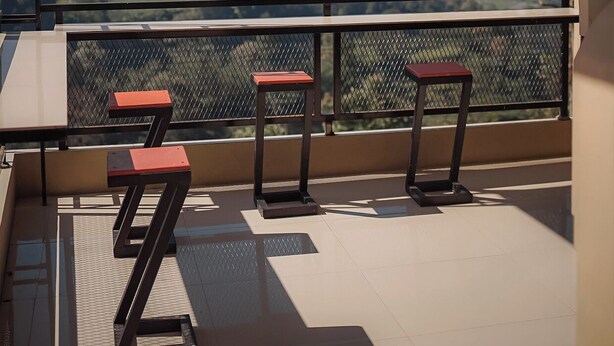 Un balcón con vistas a un paisaje montañoso, una mesa y dos sillas.