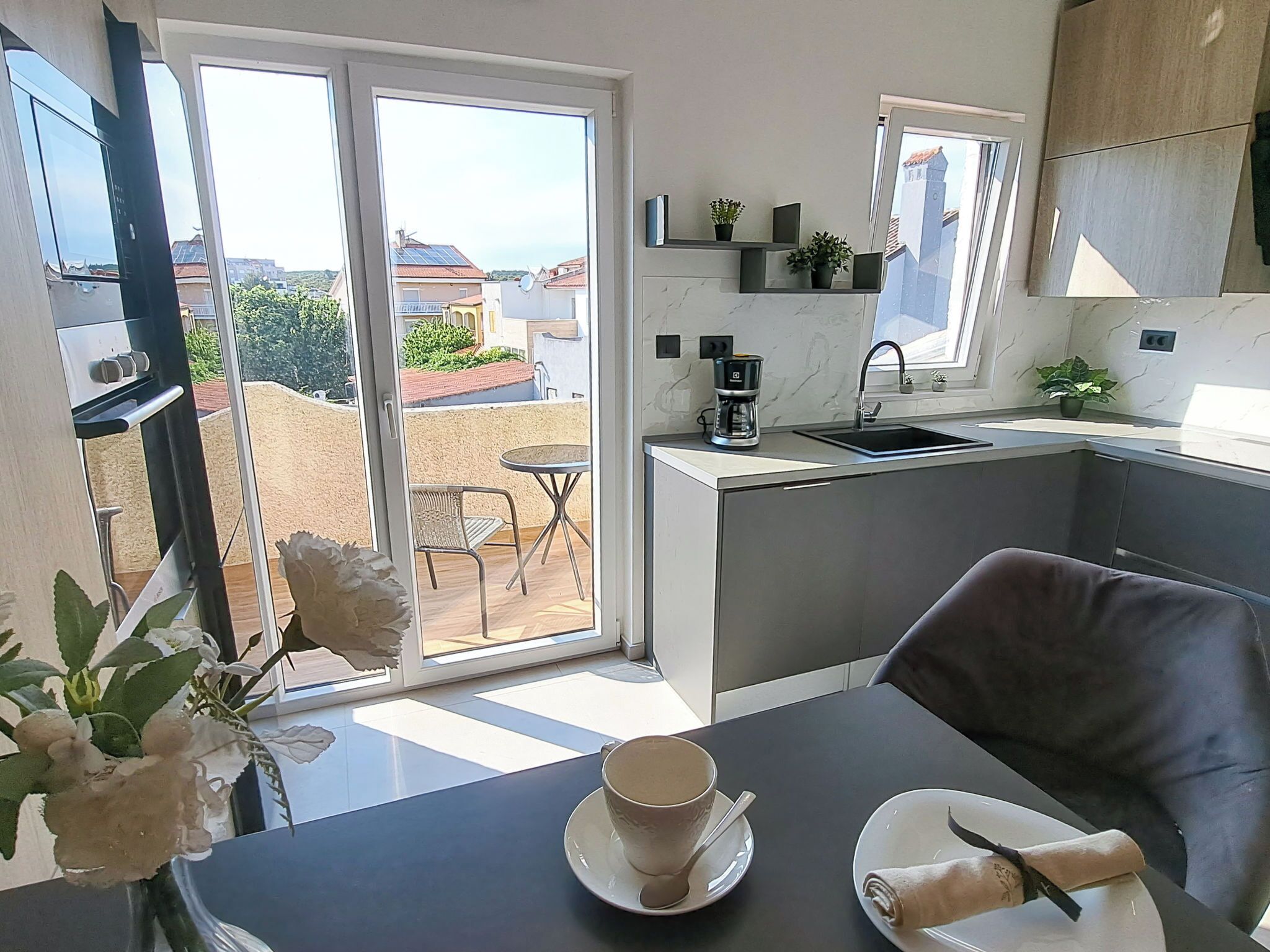 A modern kitchen with a dining area, a coffee maker, and a view of the outside.
