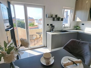 A modern kitchen with a dining area, a coffee maker, and a view of the outside. - Apartment Nona by Interhome (Medulin)