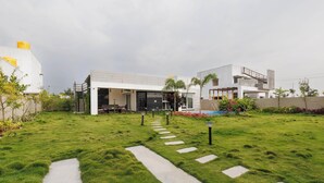 A modern house with a well-maintained lawn, a pathway leading to the entrance, and a visible outdoor seating area.