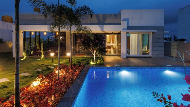 A modern house with a swimming pool, a well-maintained garden, and a patio area.