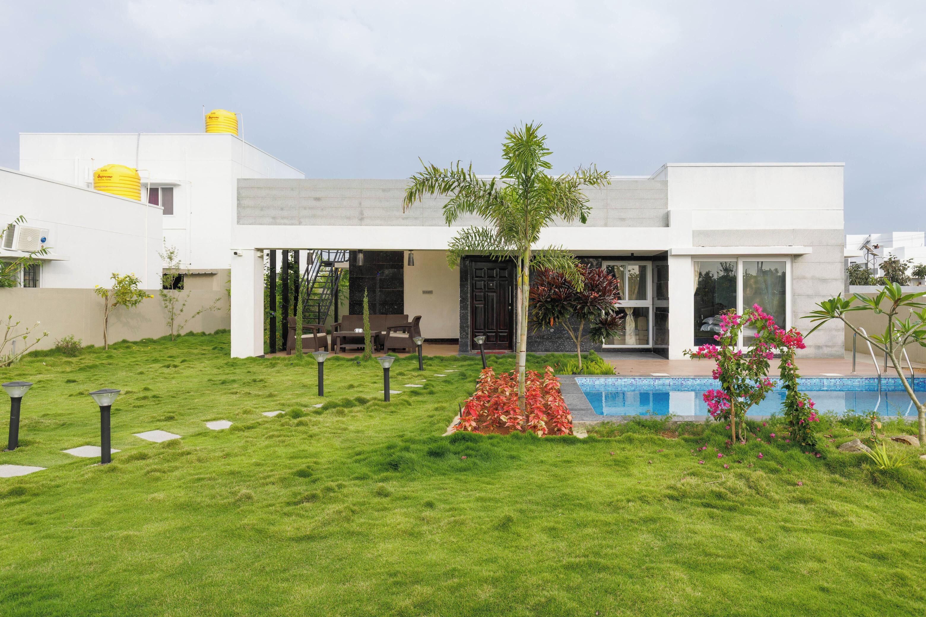 Une maison moderne dotée d’une piscine, d’une pelouse bien entretenue et d’un espace patio.