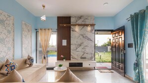 A modern living room with a sofa, a small table, a TV, and a marble accent wall.