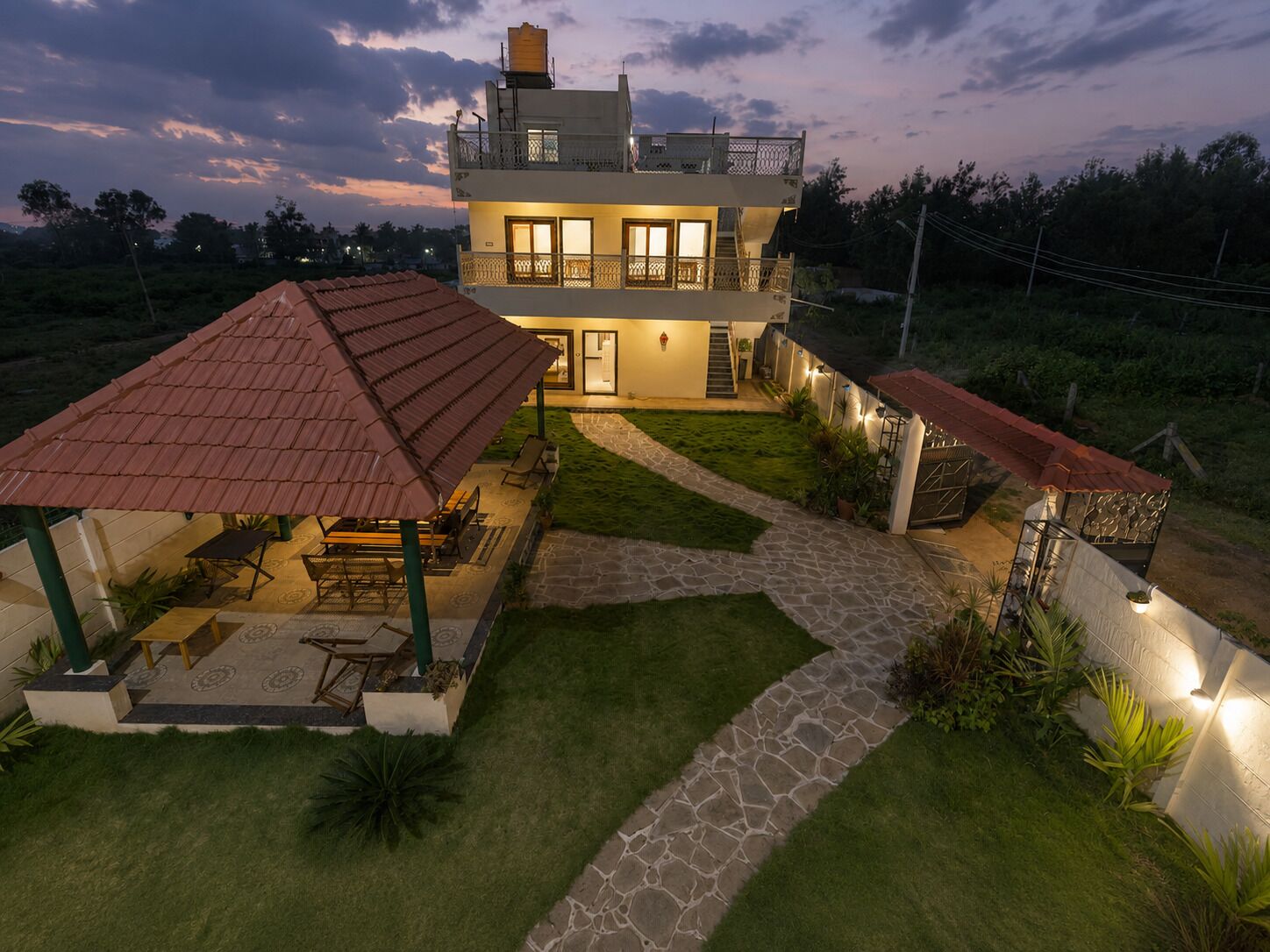 A two-story house with a covered patio, stone pathway, and a well-maintained lawn.