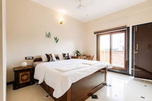 Quarto com cama, mesa de cabeceira, abajur e janela com vista.