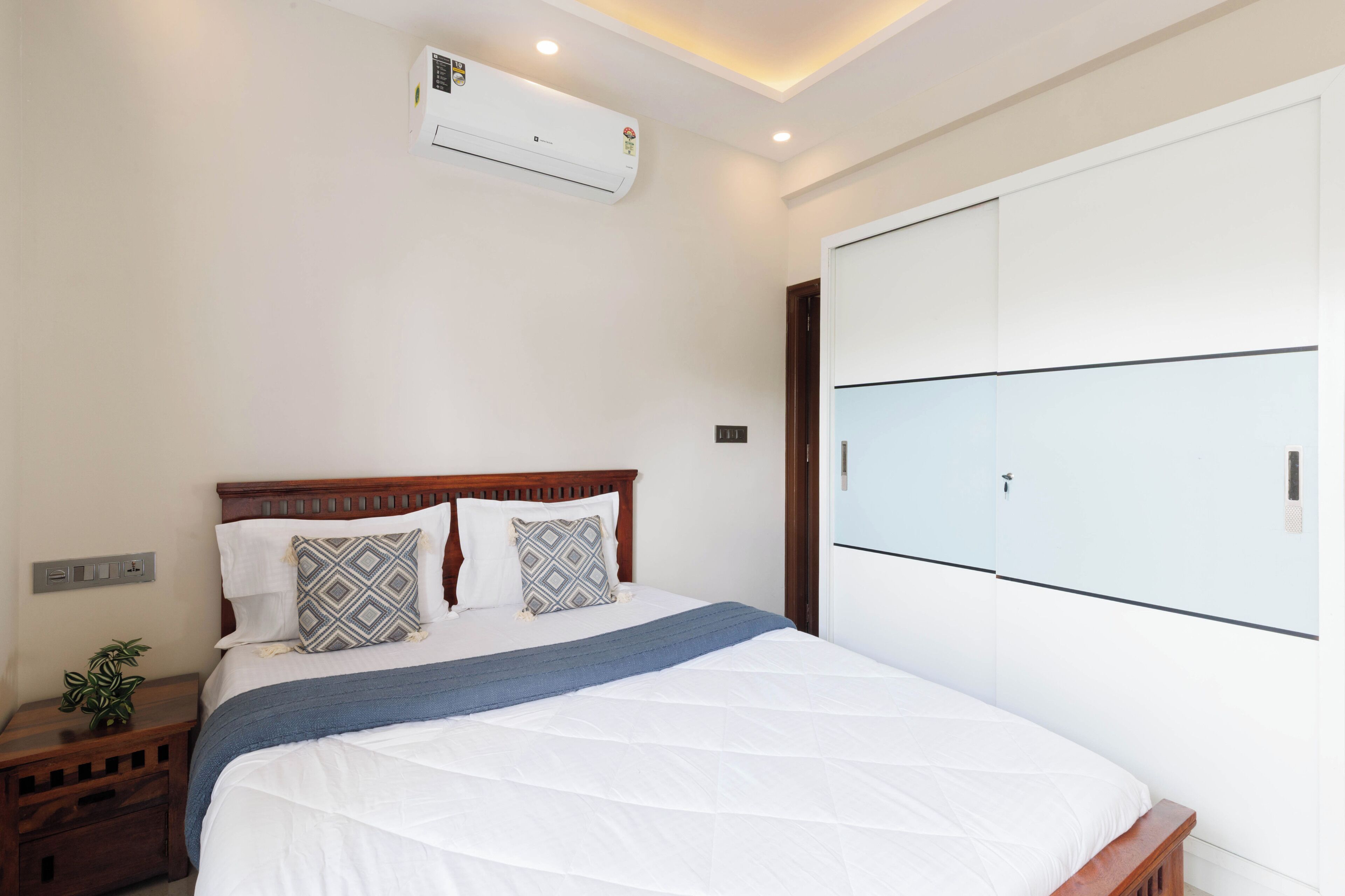 Un dormitorio con cama, mesitas de noche, aire acondicionado y armario.
