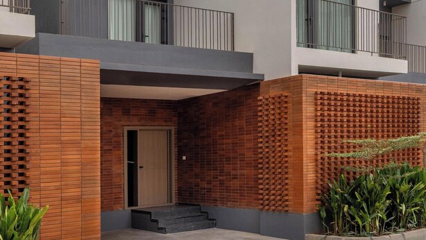 A modern multi-story building with a flat roof, balconies, and a brick facade. - Stonehill Villa Nr Airport 30min Nandi Hills (Bengaluru)