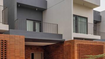 A modern multi-story building with a flat roof, balconies, and a brick facade.
