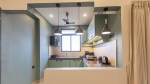 Una cocina moderna con una isla central, iluminación colgante y un ventilador de techo.