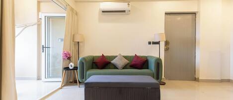 A modern living room with a sofa, a coffee table, a ceiling fan, and an air conditioning unit.