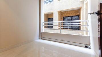 A room with a tiled floor, a white railing, and a view of a building with multiple windows and balconies.