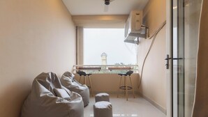 Una habitación pequeña con ventana, una mesa con sillas, un sillón de saco y un cerramiento de vidrio corredero.