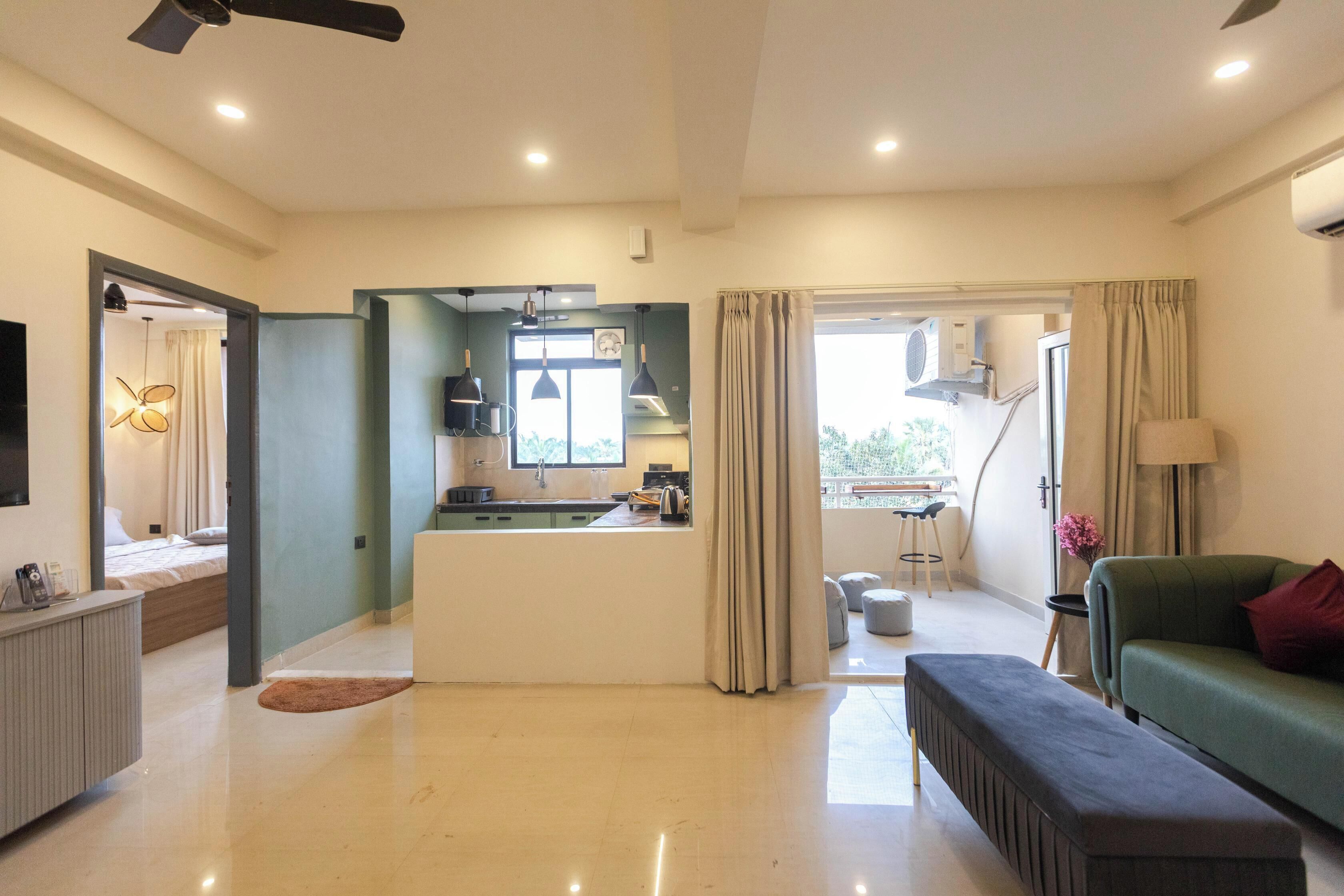 A modern living room with a sofa, a bench, a kitchen area, and a dining table.