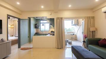 A modern living room with a sofa, a bench, a kitchen area, and a dining table.