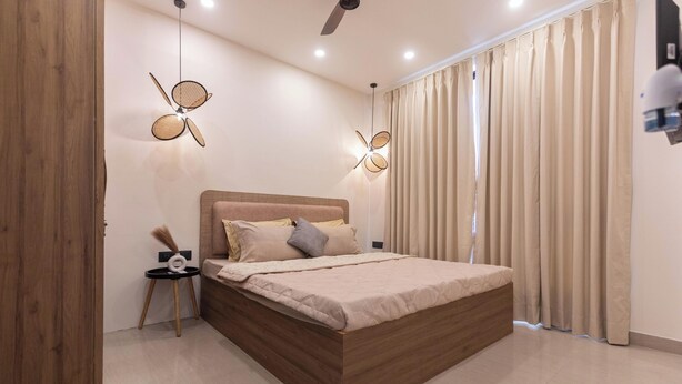 Un dormitorio moderno con una cama de madera, dos lámparas colgantes, un ventilador de techo y un amplio ventanal con cortinas.