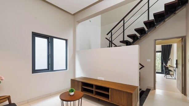 Un salon moderne avec un meuble de rangement en bois pour les appareils multimédias, un escalier et une vue sur l’espace salle à manger.