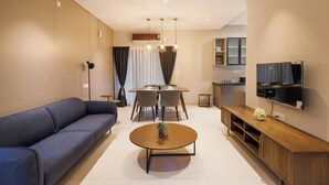 Un salon moderne comprenant un canapé, une table à manger, des chaises, une table basse, un téléviseur et un coin cuisine.