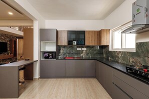 Una cocina moderna con salpicadero de mármol, gabinetes grises y una isla integrada con taburetes de bar.