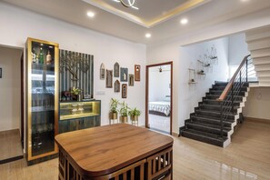 A modern interior with a wooden table, a glass cabinet with bottles, a staircase, and wall-mounted mirrors. - Blossom Ranch Villa by Stayjade Pool1hr Hsr (Denkanikota)