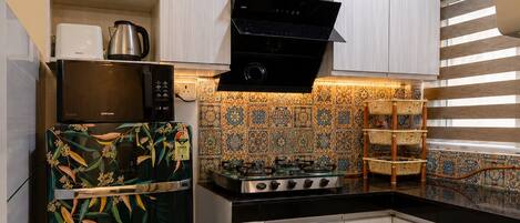 A kitchen with a microwave, stove, and a refrigerator with a floral pattern.