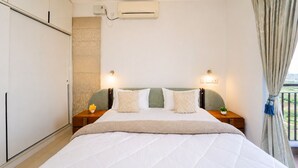 A bedroom with a bed, nightstands, an air conditioning unit, and a view through a window. - Prism by Red Olive4 Bhkomrecr Beaches it Park (Tirupporur)