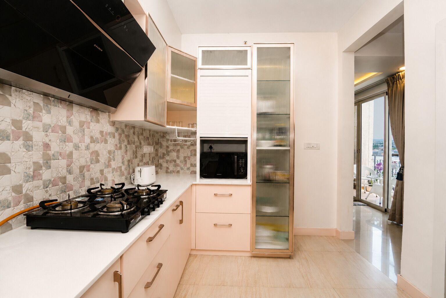 A modern kitchen with a gas stove, microwave, and a glass-fronted pantry.