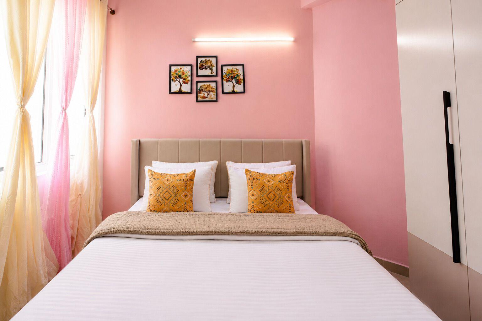 Une chambre à coucher avec un lit, des oreillers, une tête de lit et des œuvres d’art murales.
