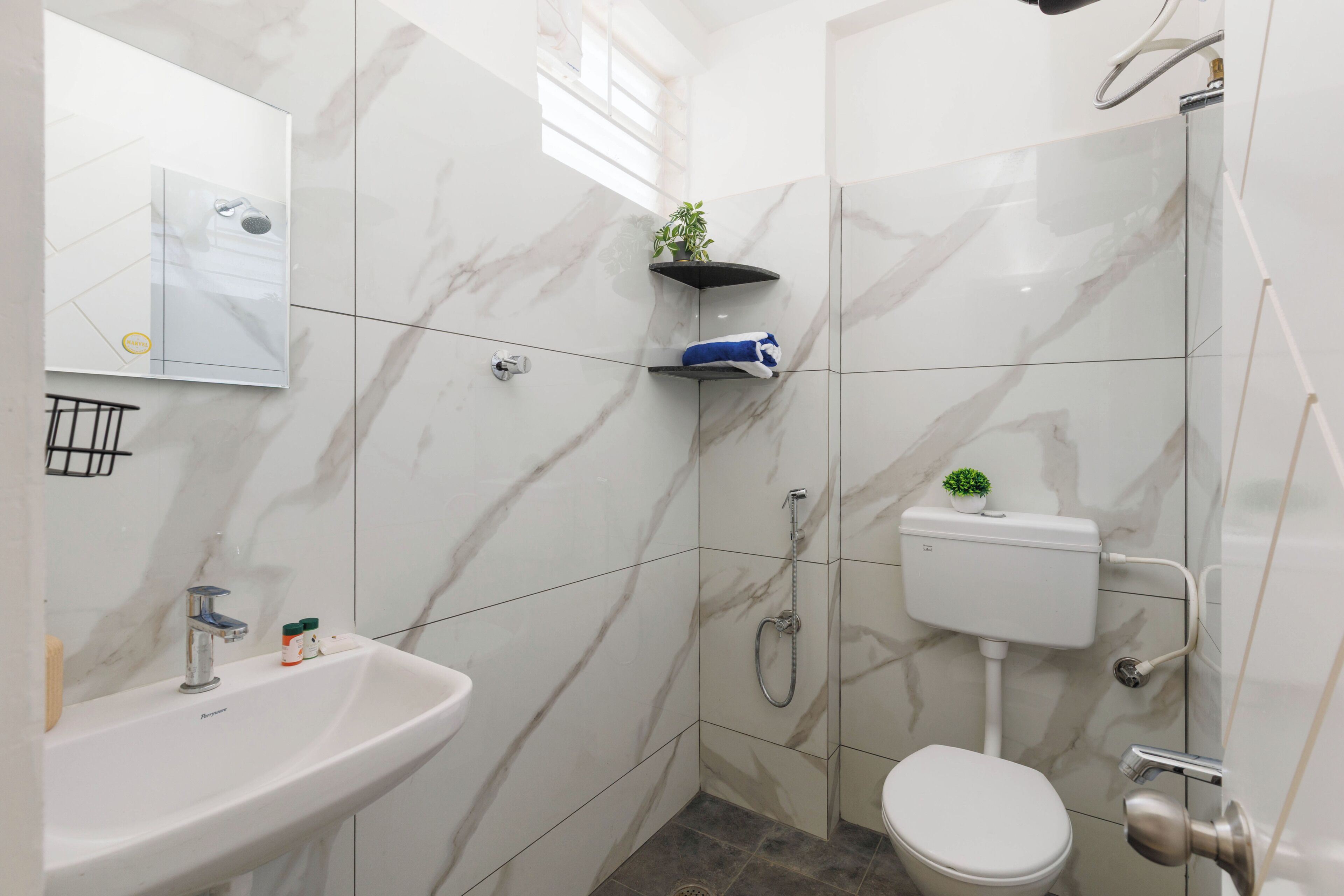 A bathroom with a sink, toilet, shower, and marble tiles.