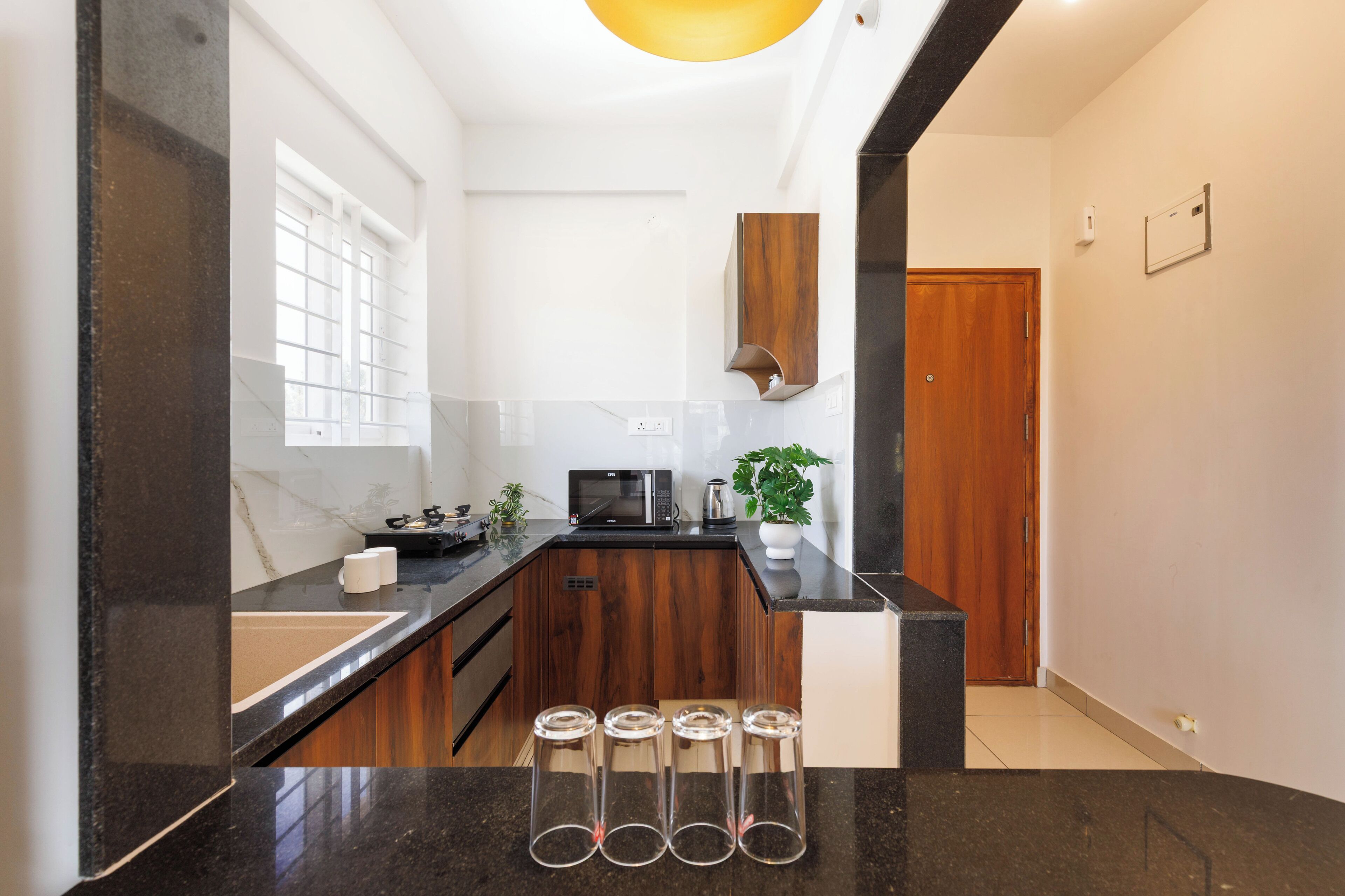 A modern kitchen with a black countertop, wooden cabinets, and a microwave.
