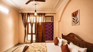 Ein Schlafzimmer mit Bett, Vorhängen, Deckenventilator, einer Wand mit einer Dekorplatte und einem Fenster mit Blick.