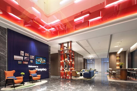 A modern lobby with a reception desk, seating area, and a decorative red column.