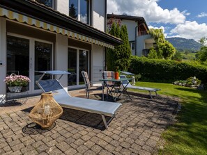 Eine Terrasse mit Gartenmöbeln, einer Korlampen und Blick auf eine Berglandschaft.
